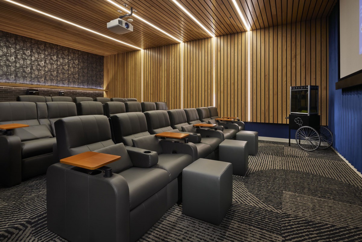 A modern home theater setup with comfortable reclining seats and wooden paneling.