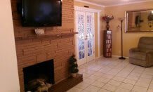 A cozy living room with a brick fireplace and mounted television, featuring French doors and elegant interior design.
