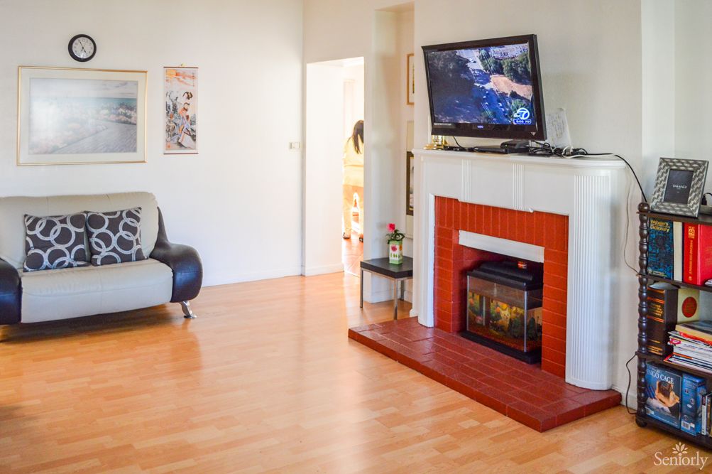 A cozy living room with a fireplace and TV, featuring wood flooring and a comfortable sofa.