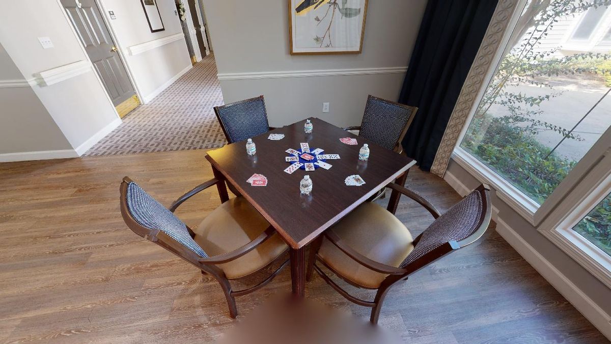 A wooden table with four chairs in a well-decorated room, featuring artwork on the wall.