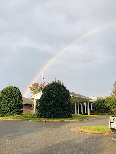A beautiful rainbow appears above a serene building on a cloudy day.