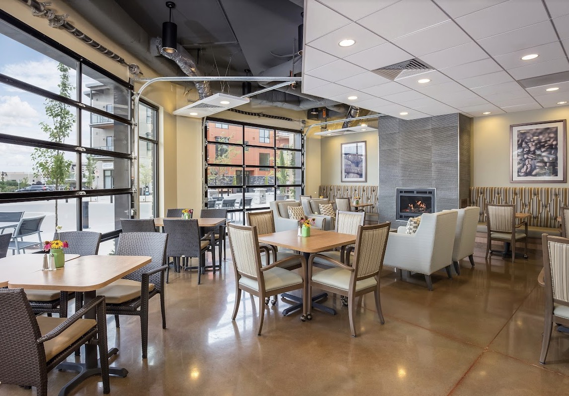 A modern restaurant interior with a spacious dining area, featuring large windows and a cozy fireplace.