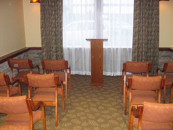A small conference room with rows of chairs facing a podium in front of a window.