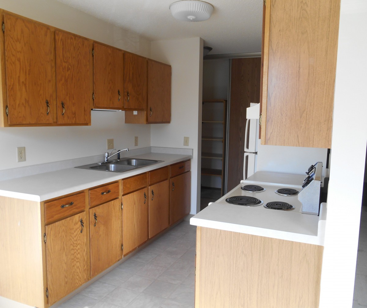 A compact kitchen with wooden cabinets and a stove.
