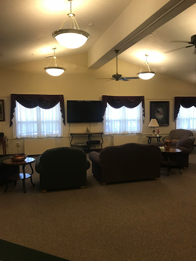 A cozy lounge area with sofas, natural light from large windows, and ceiling fans for comfort.