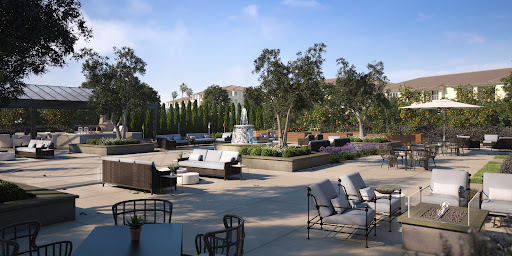 A serene outdoor lounge area featuring comfortable seating and a tranquil water fountain, surrounded by lush greenery.