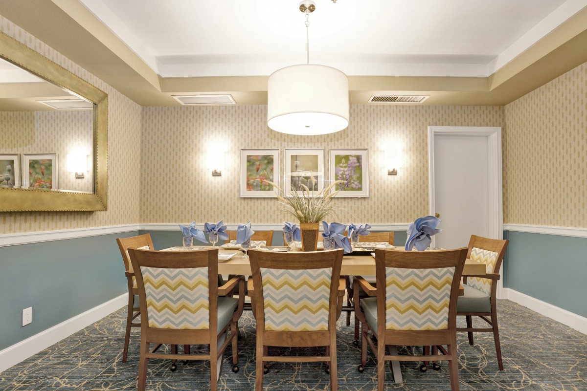 A well-decorated dining room with a central table and chairs, elegant lighting, and wall art.