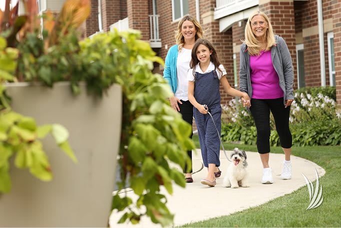 A family walking their dog in a residential neighborhood.