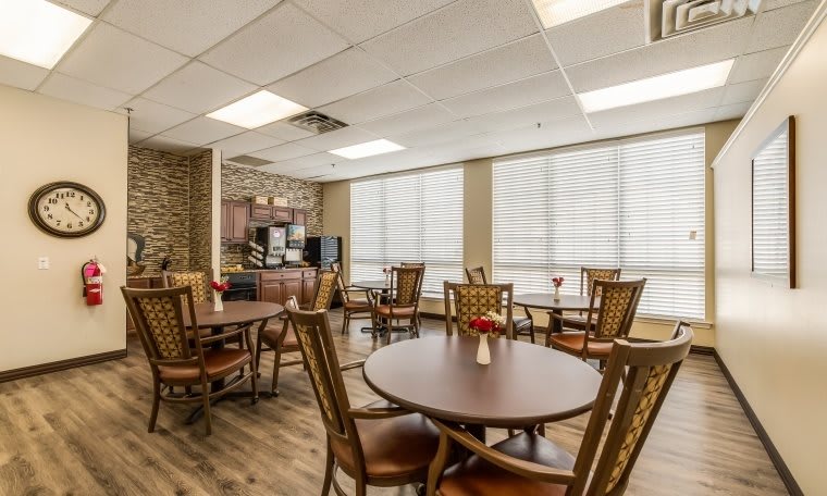 A bright and inviting dining area with several tables and chairs, featuring large windows allowing natural light to fill the room.