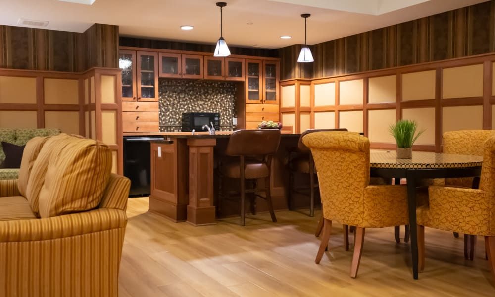 A cozy home bar with wood paneling, bar stools, and pendant lighting.