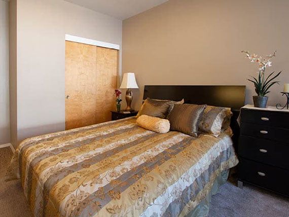 A cozy bedroom featuring a neatly made bed with decorative pillows and a bedside lamp.