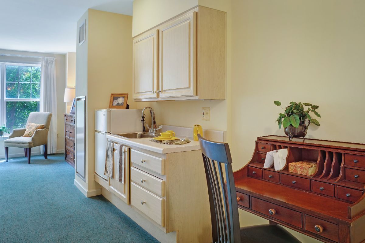 A compact kitchen area with wooden cabinets and a small desk for workspace.