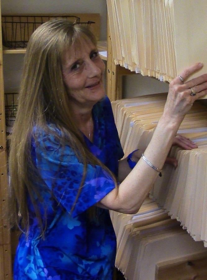 A woman organizing files on a shelf in an office.
