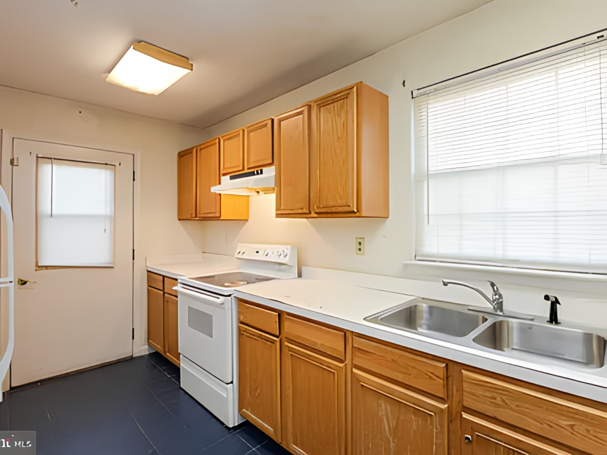 A clean and organized kitchen with wooden cabinets, a stove, and a double sink.