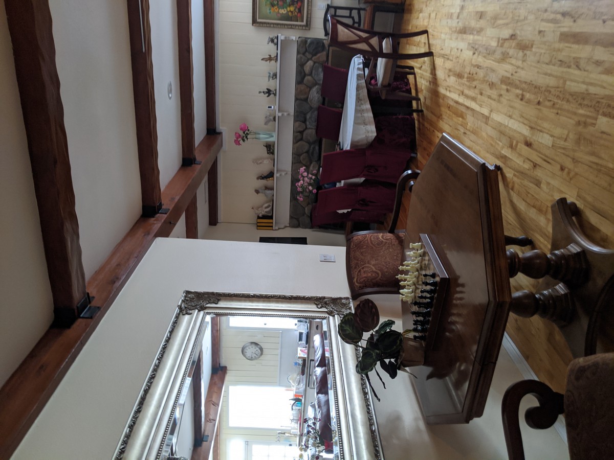 A cozy living room featuring a piano, mirror, and elegant furniture with a wooden floor.
