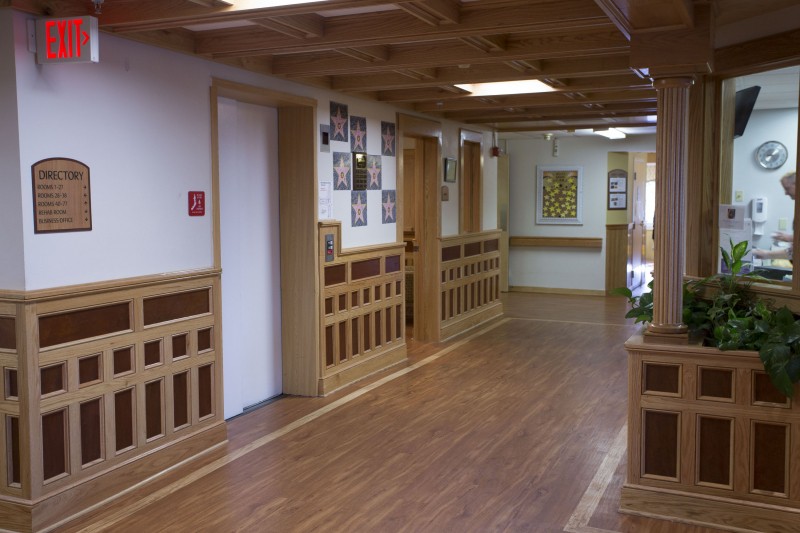 A hallway with wooden paneling and flooring in a building interior.