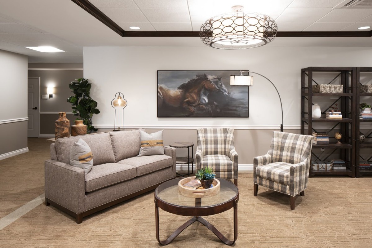 A cozy living room with a sofa, two plaid armchairs, a round coffee table, and decorative artwork on the wall.