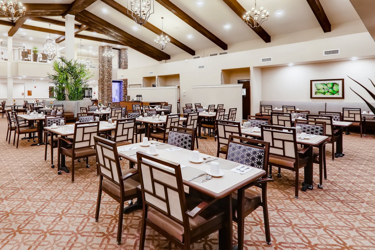 A spacious restaurant dining area with neatly arranged tables and elegant chandeliers.