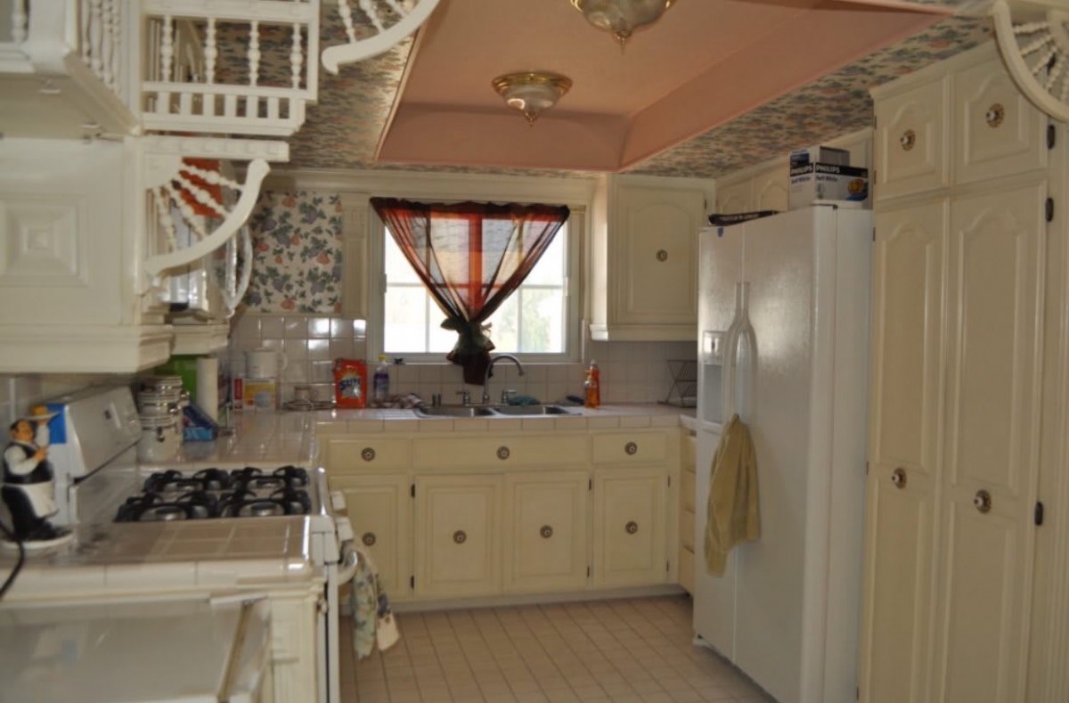 A vintage-style kitchen with cream cabinets and a classic white fridge.