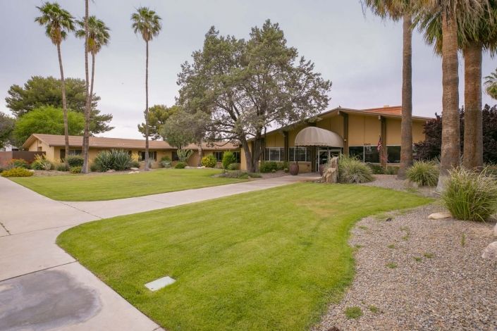 A scenic view of a building surrounded by a well-kept lawn and tall palm trees.