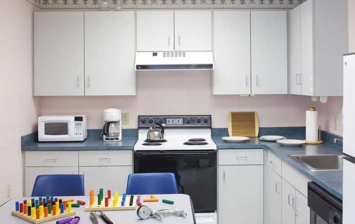 A classroom-style kitchen setup with appliances and toys on the table.
