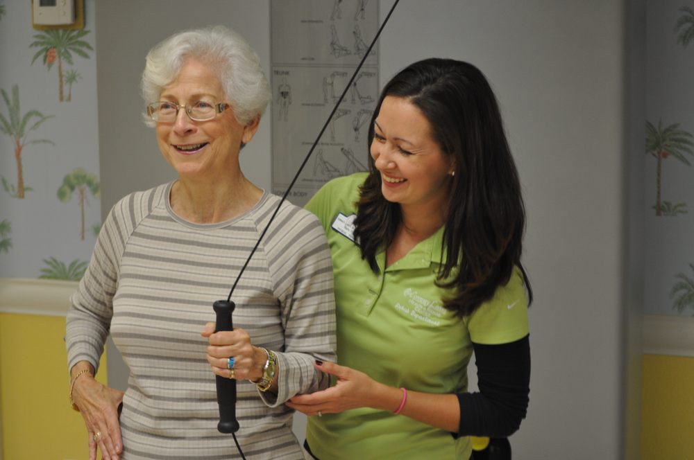 An elderly woman receiving assistance during a physical therapy session.
