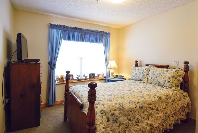 A cozy bedroom with a floral bedspread and blue curtains.