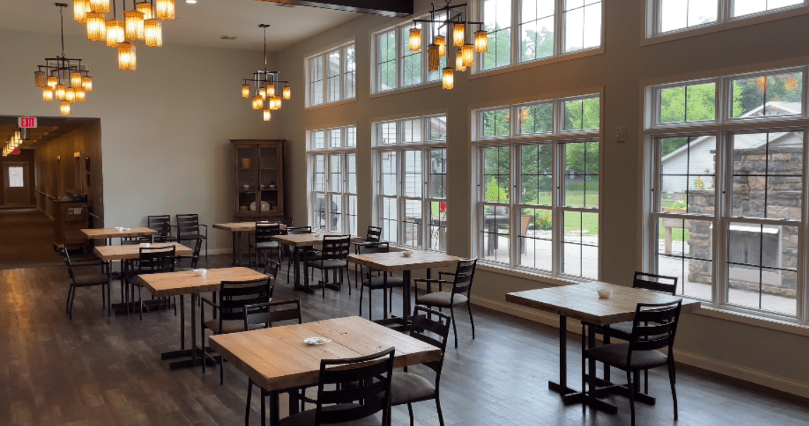 A modern restaurant interior with wooden tables and large windows.