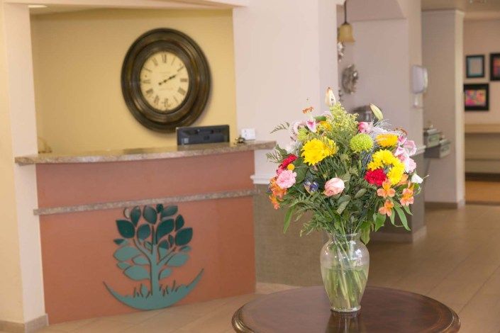 A reception area with a flower arrangement and a clock in the background.