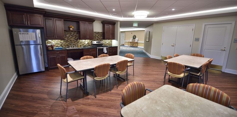A modern kitchen and dining area featuring wooden tables and chairs with wood flooring.