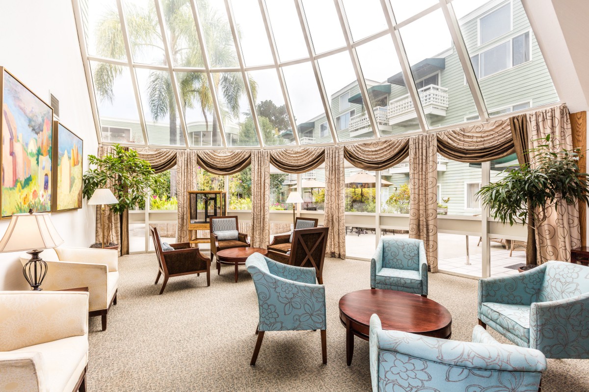 A spacious lobby seating area with elegant furniture and a glass ceiling that lets in natural light.
