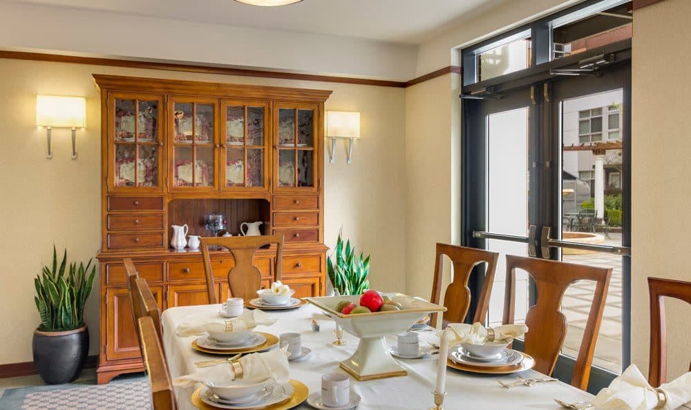A well-set dining room table with a china cabinet in the background.