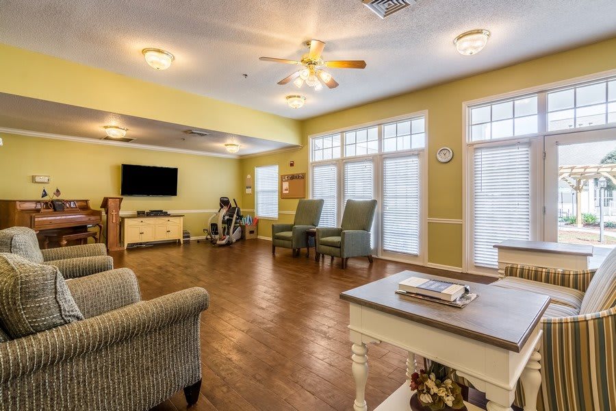 A cozy living room with large windows, comfortable seating, and a television.