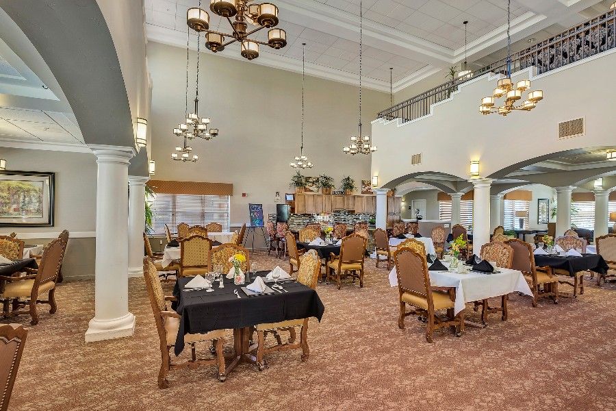 A spacious dining room with elegant chandeliers and neatly arranged tables and chairs.