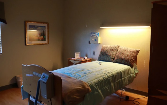 A dimly lit hospital room featuring a single bed and medical equipment.