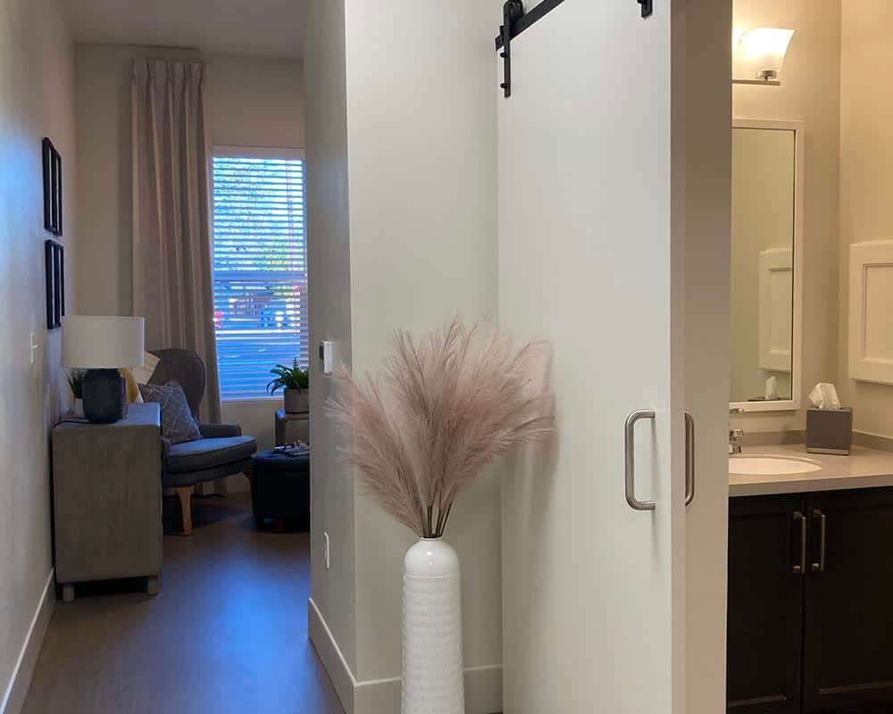 A modern living space with a sliding barn door, featuring a tall vase with pampas grass.