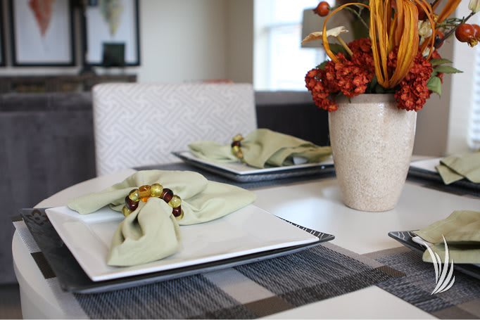 A neatly arranged dining table with green napkins and an elegant centerpiece.