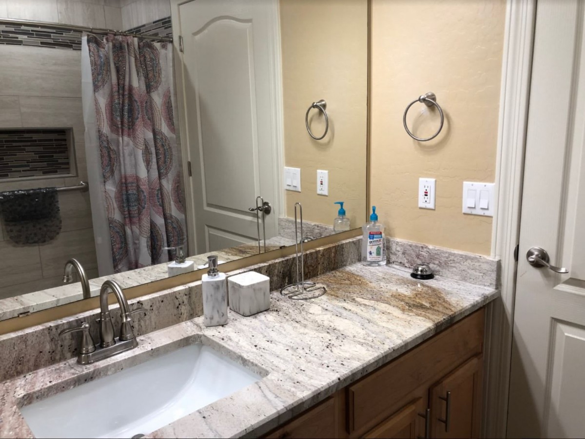 A clean and modern bathroom with a sleek marble countertop and large mirror.