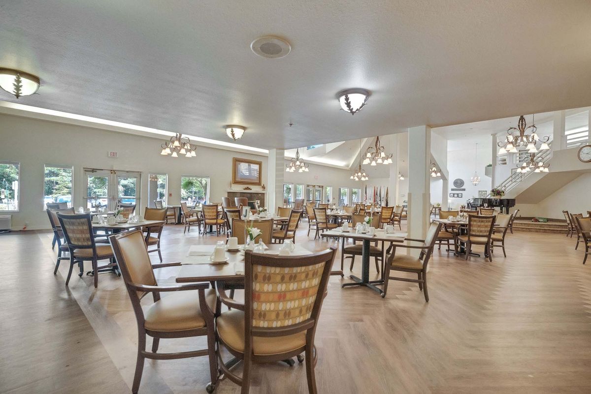 An elegant dining area with neatly arranged tables and chairs, featuring wooden flooring and stylish lighting.