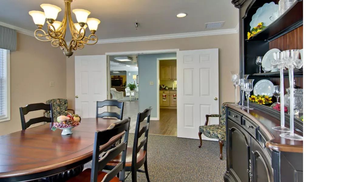 A well-furnished dining room featuring a table, chairs, and a cabinet with decorative items.