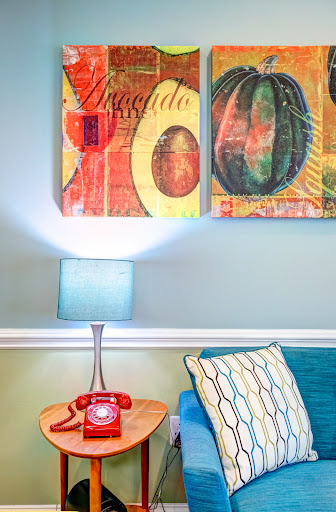 A vibrant and stylish living room featuring colorful artwork, a cozy couch, and a retro lamp.