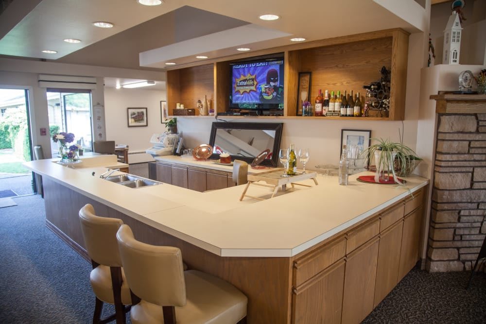 A modern home bar setup with a countertop, seating, and a television display.