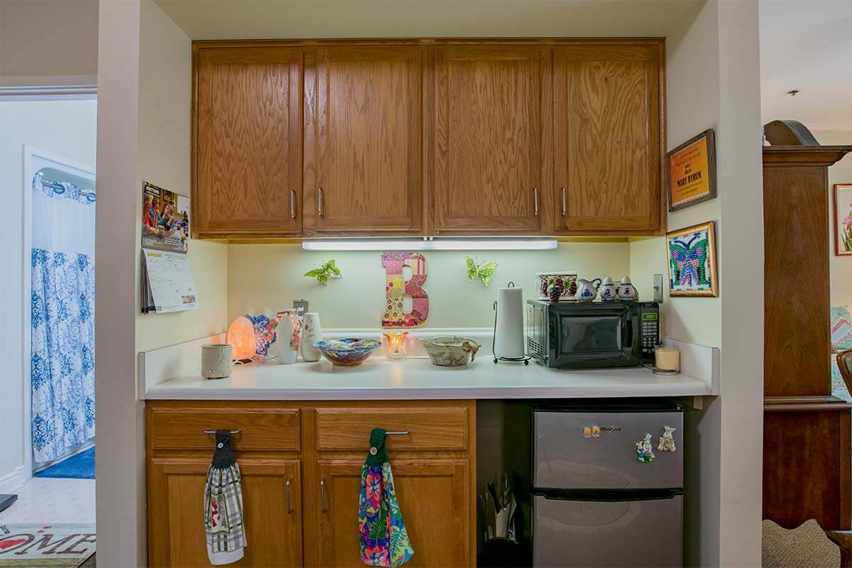 A compact kitchen setup with wooden cabinets, a microwave, and a mini fridge.