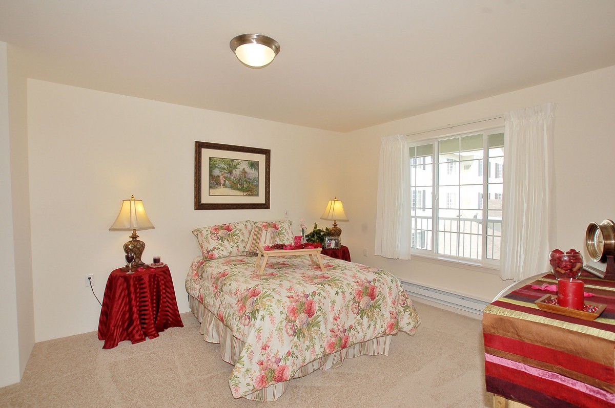 A cozy bedroom with floral bedding and warm lighting.