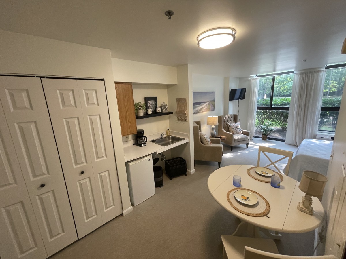 A cozy studio apartment featuring a kitchenette, dining area, and a living room with natural light.