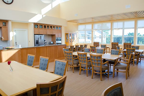 A bright dining area with wooden tables and chairs, featuring abundant natural light.