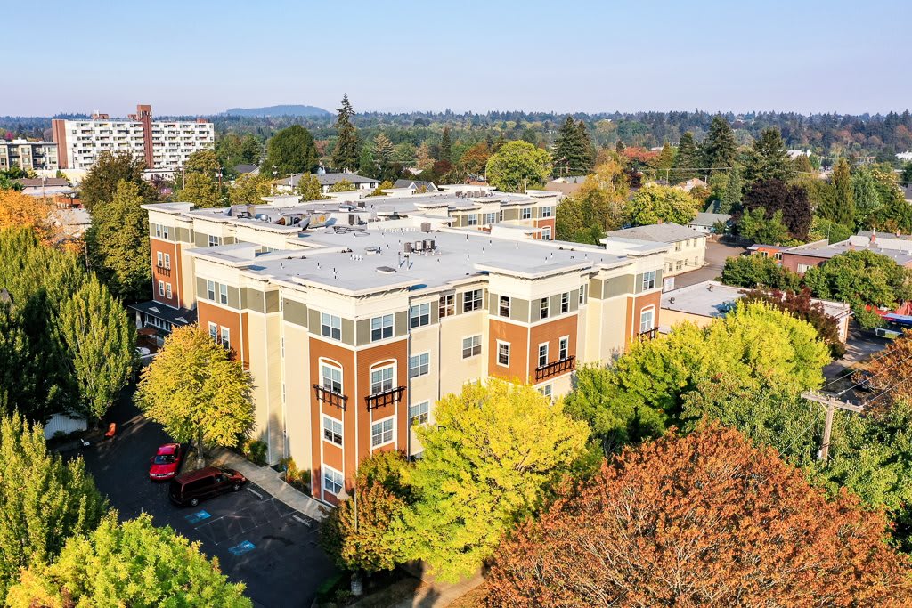 Aerial view of an apartment building surrounded by colorful autumn trees in a suburban area.