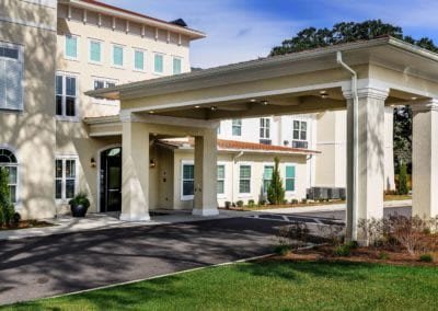 A modern building entrance with a covered driveway and landscaped surroundings.