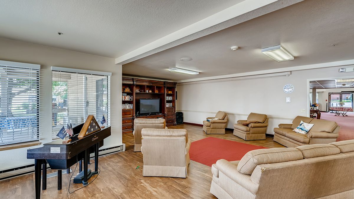 A cozy living room with multiple armchairs, a television, and built-in bookshelves.