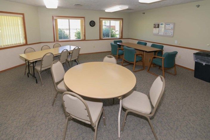 A multipurpose office meeting room with tables and chairs arranged for group discussions.